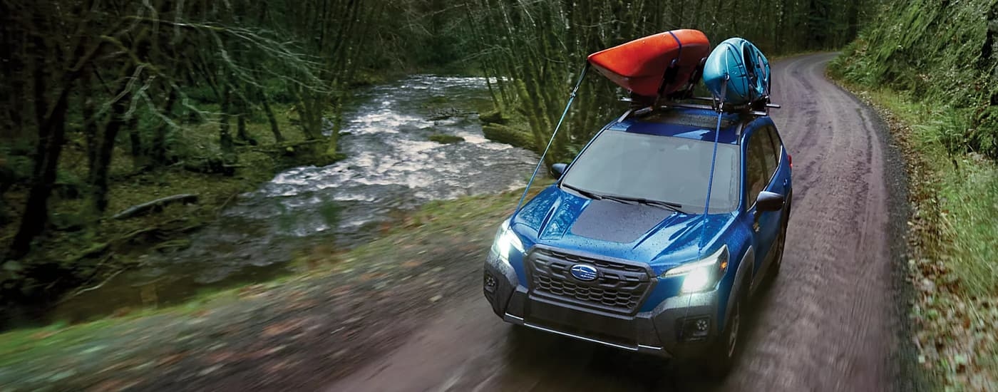 Blue 2023 Subaru Forester driving down a road.