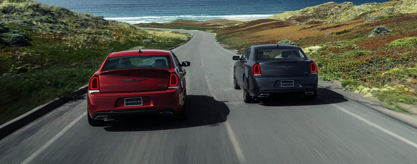 A red and a black 2021 Chrysler 300 driving towards the ocean