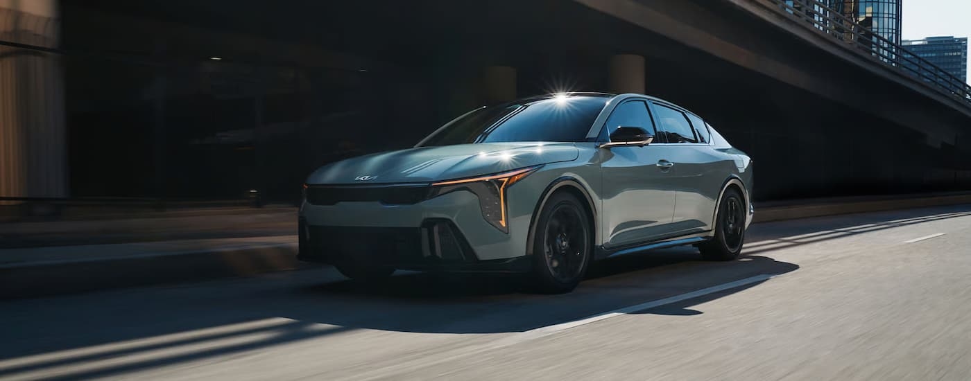 A gray 2026 Kia K4 driving down a city street