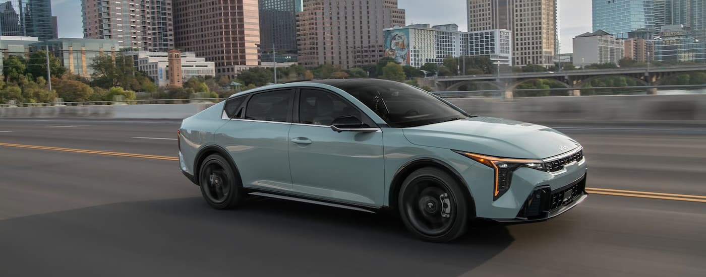A gray 2026 Kia K4 driving in a city