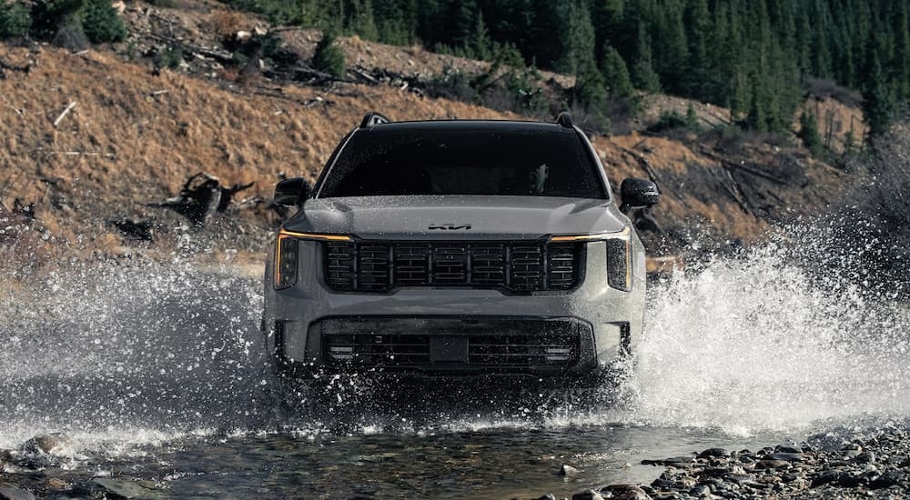 Front of a grey 2026 Kia Sorento driving over a shallow pond.