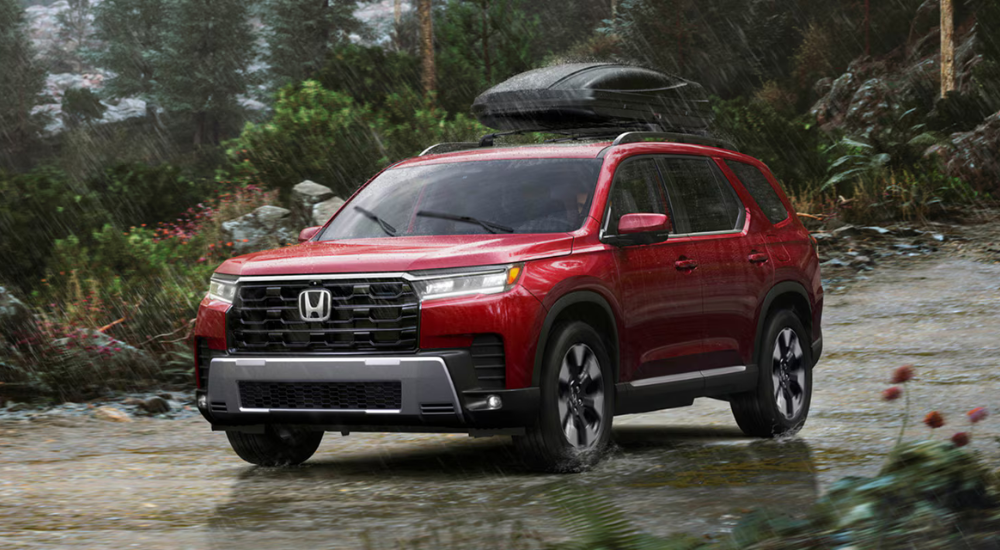 Red 2026 Honda Pilot with a roof box driving in the rain