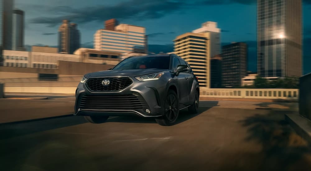 Black 2026 Toyota Highlander driving down a city street.