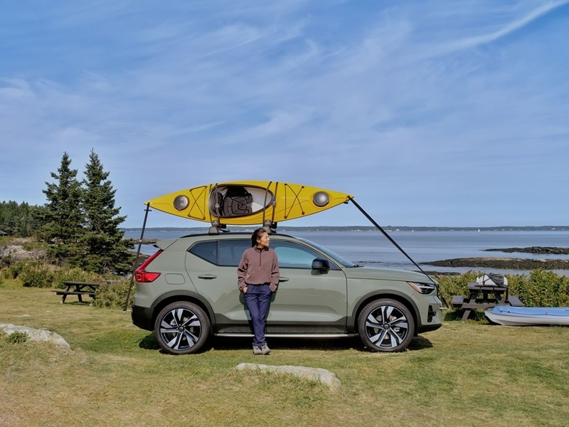 Man standing against parked Volvo XC40 with canoe on rooftop from Certified Pre-Owned Volvo Dealer near Me