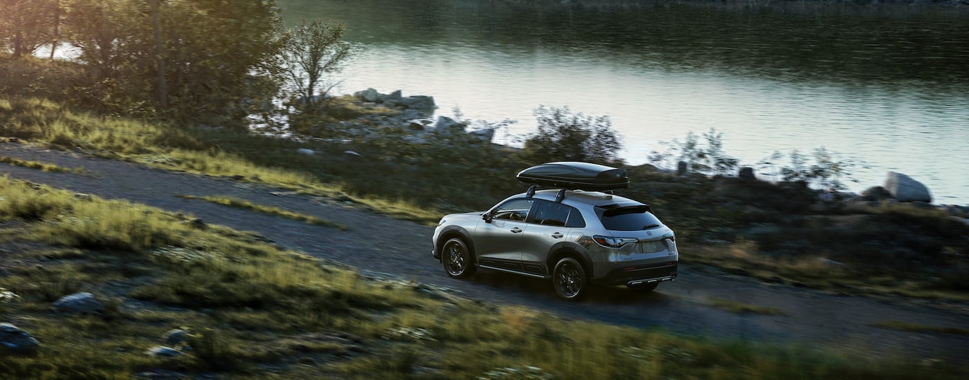 Rear of a silver 2026 Honda HR-V driving near a lake.