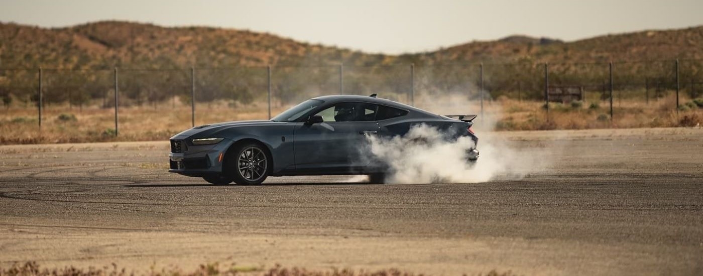 Side of a grey 2024 Ford Mustang Dark Horse performing a burnout.