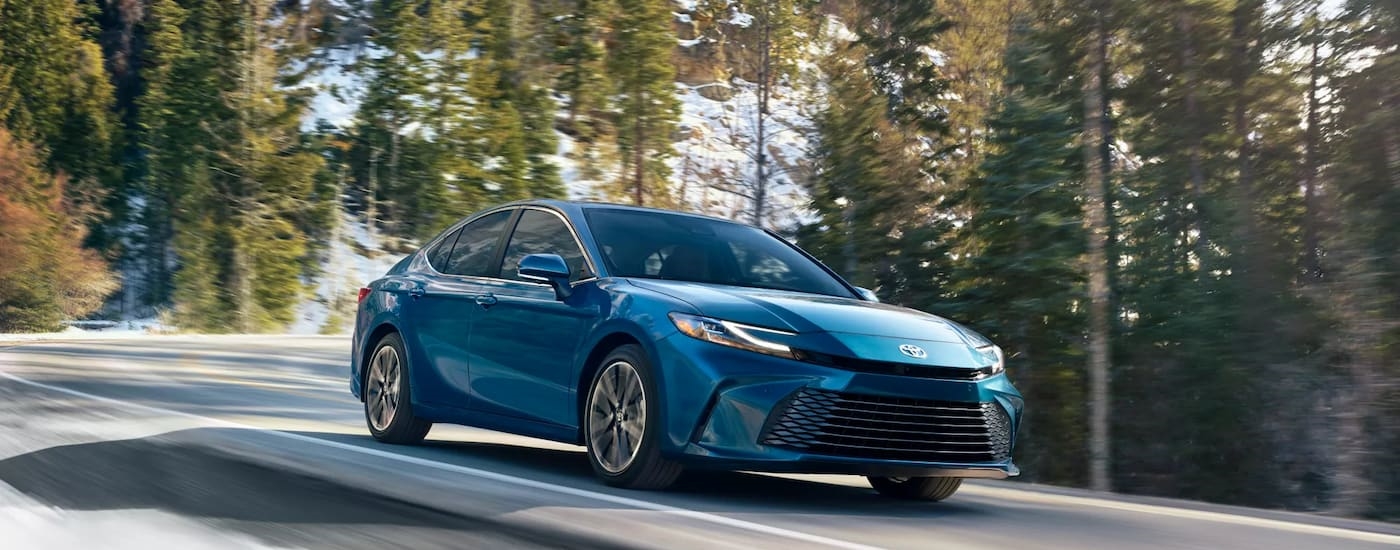 Blue 2025 Toyota Camry driving around a bend.