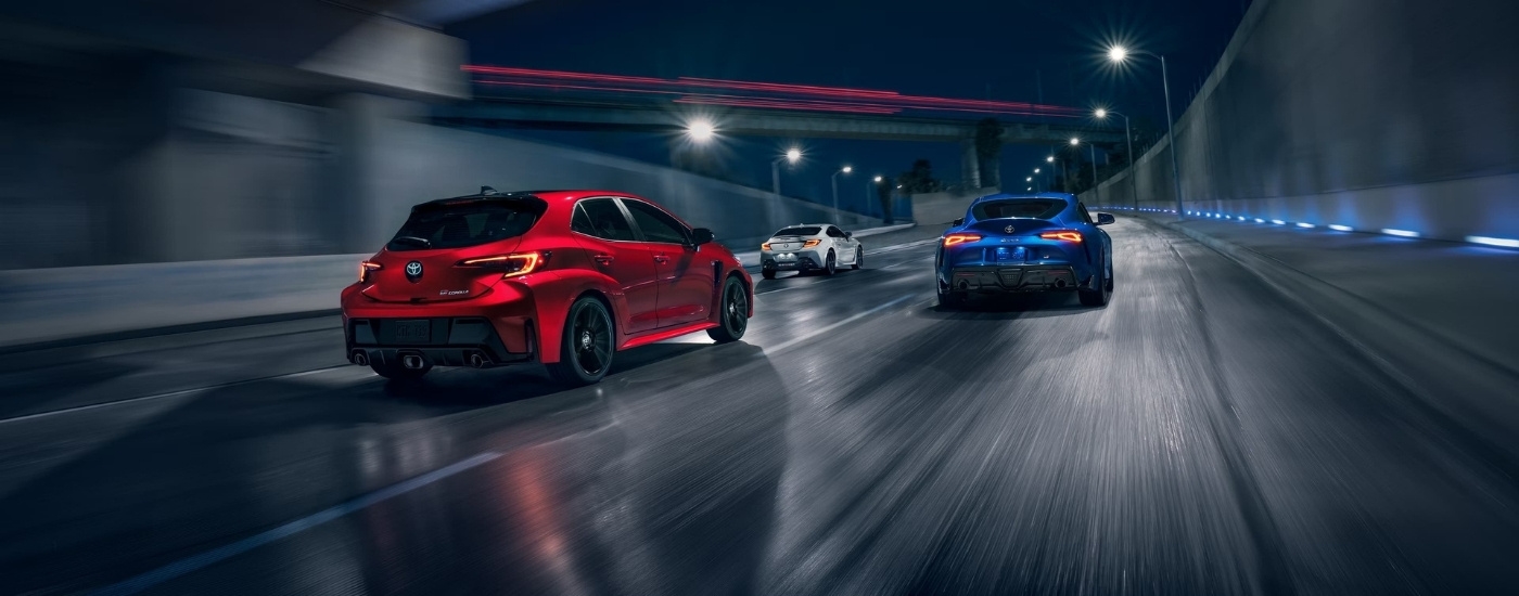 Red 2025 Toyota GR Supra Premium, white GR86 Premium, and blue GR Corolla Premium Plus driving on a highway