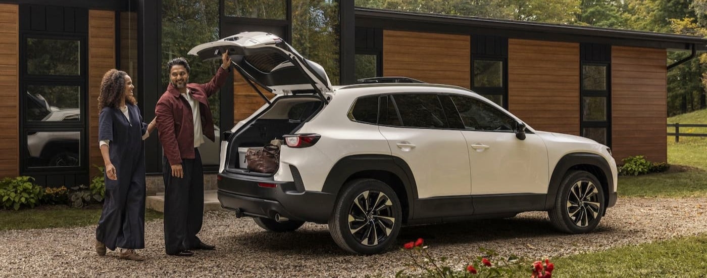 Two people standing near the open hatch on a white 2026 Mazda CX-50.
