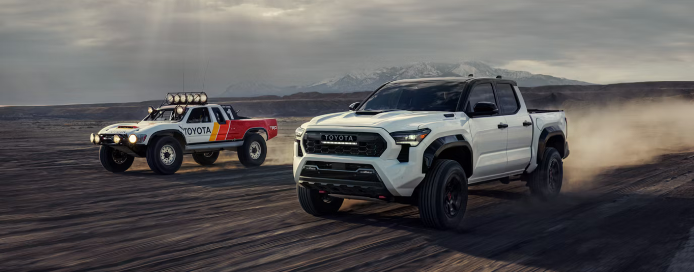 White 2026 Toyota Tacoma TRD Pro racing next to a Toyota rally truck