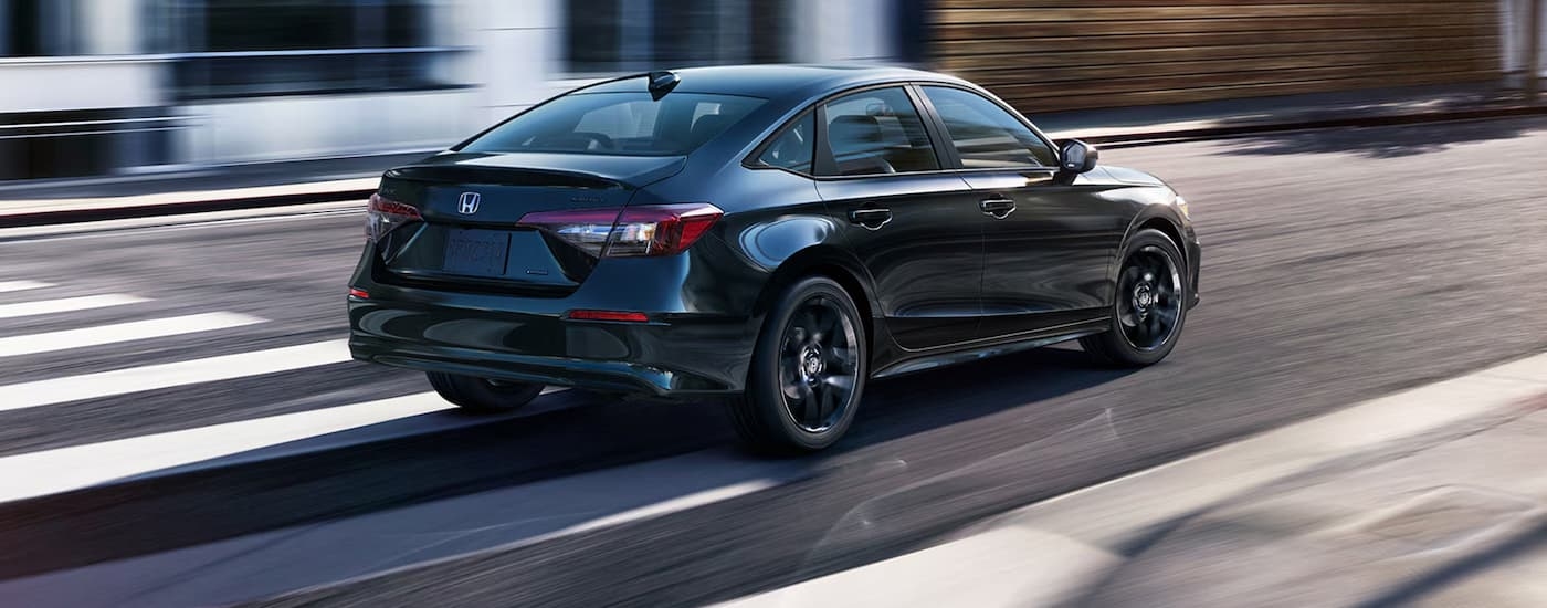 Rear of a black 2026 Honda Civic driving down a city street.