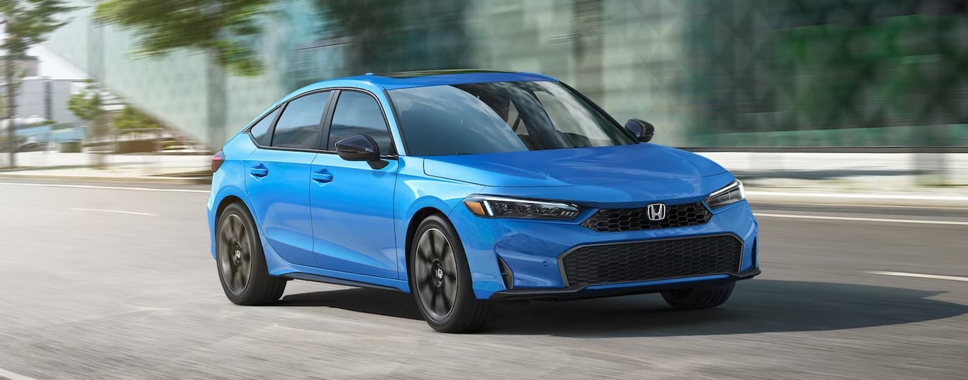Blue 2026 Honda Civic driving down a road.
