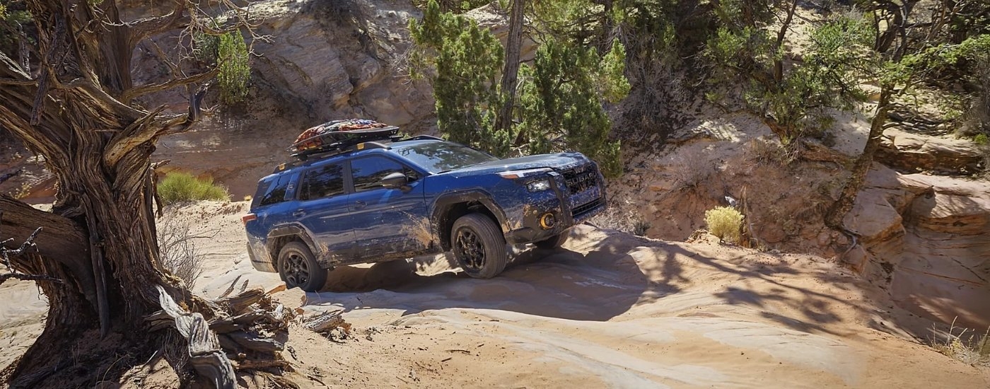 Blue 2026 Subaru Outback driving on a trail