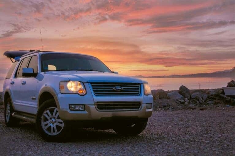 White Ford SUV with the back open on a beach at sunset