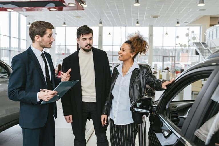 Man and a woman buying a car in a dealership