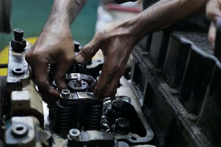 A person is working on a car engine with hands marked with oil