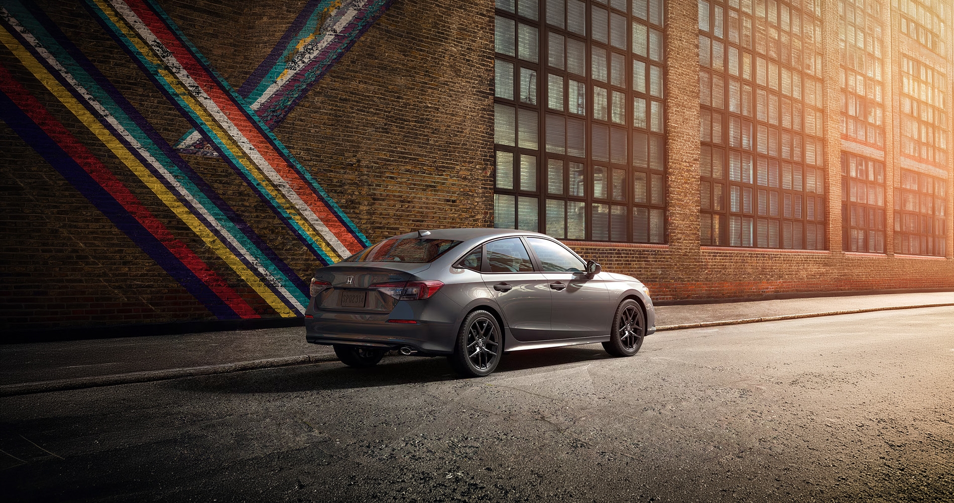 Honda Civic sedan parked on a city street beside a colorful mural, showcasing sleek exterior design and modern styling