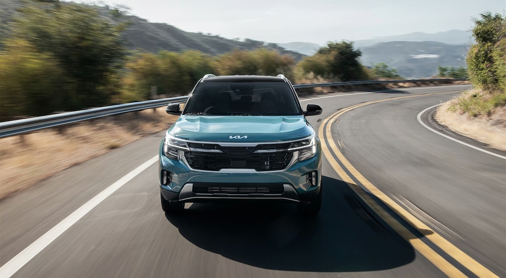 Front of a blue 2026 Kia Seltos driving around a bend.
