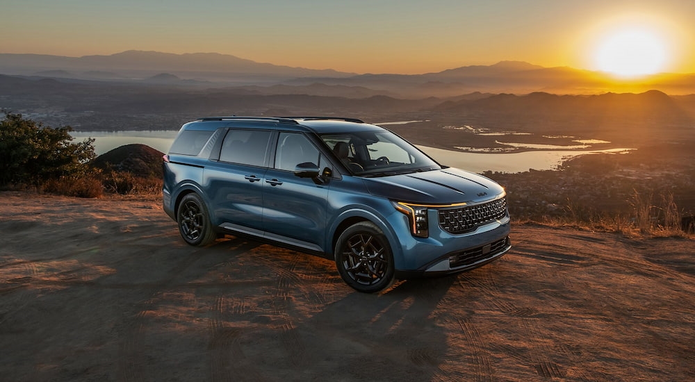Dark blue 2026 Kia Carnival parked off-road.