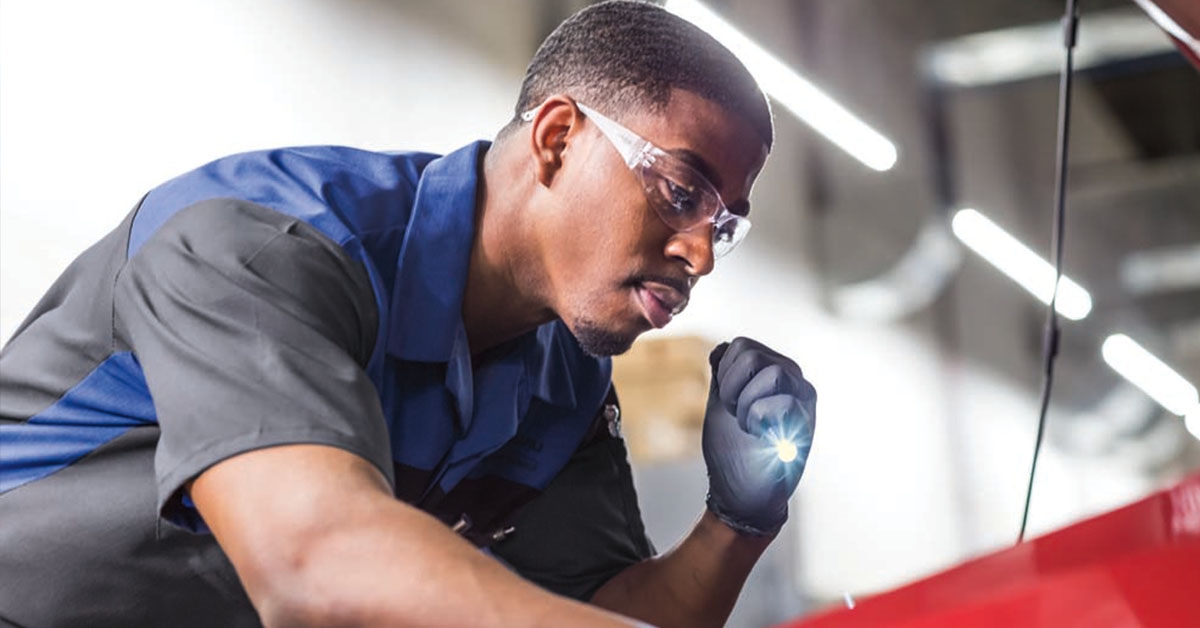 Technician inspecting vehicle at a Subaru dealership