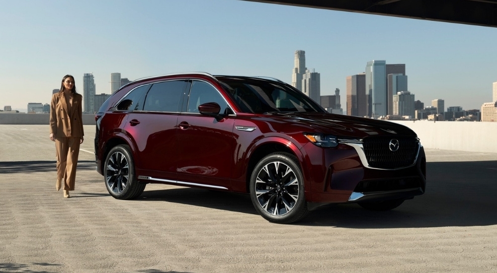 Person walking past a maroon 2026 Mazda CX-90 for sale