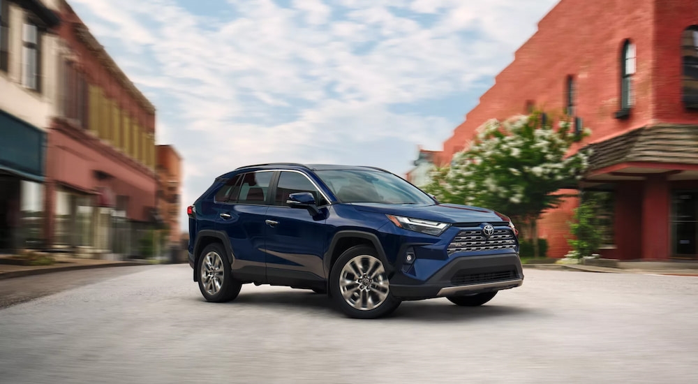 Side of a dark blue 2026 Toyota RAV4 rounding a corner.