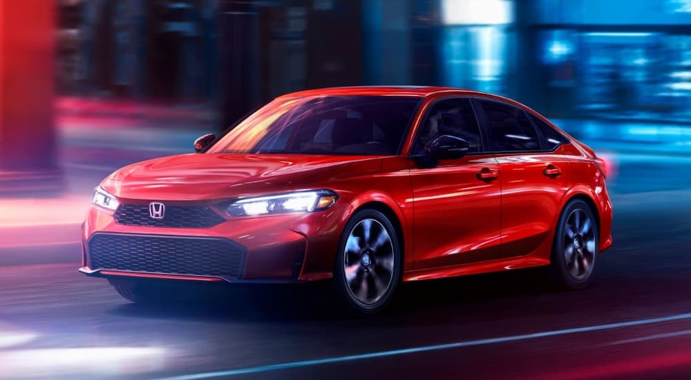 A red 2026 Honda Civic driving in a city at night