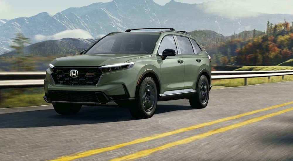 A green 2026 Honda CR-V TrailSport driving down a highway