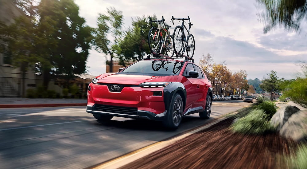 Red 2026 Subaru Solterra driving down a road.