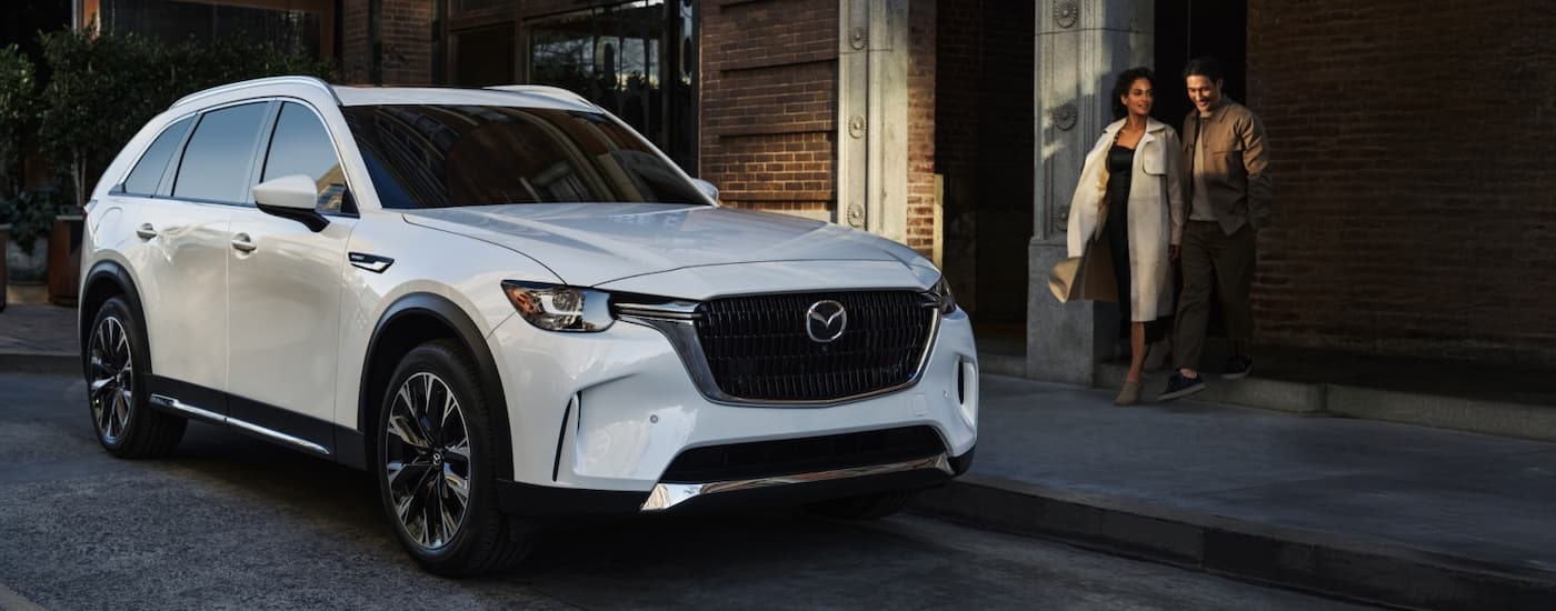 White 2026 Mazda CX-90 parked next to a brick building
