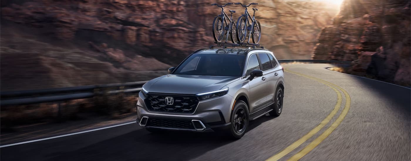 Grey 2026 Honda CR-V Hybrid driving around a bend.