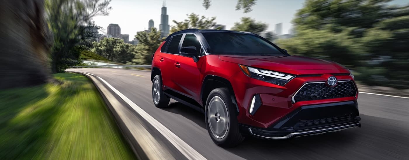Red 2026 Toyota RAV4 driving down a road.
