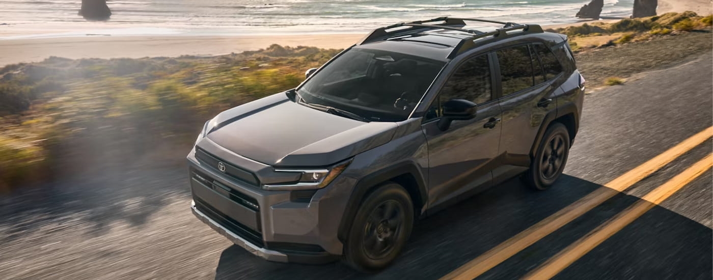Grey 2026 Toyota RAV4 driving down a road.
