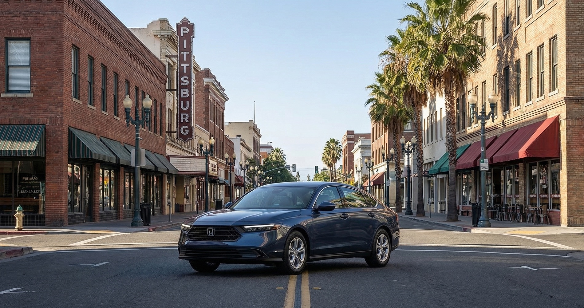 2026 Honda Accord driving through downtown Pittsburg, CA with historic storefronts, palm-lined street, and urban Delta region setting in the background