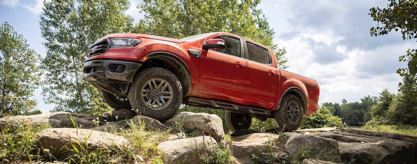 Red 2021 Ford Ranger driving off-road up a hill.