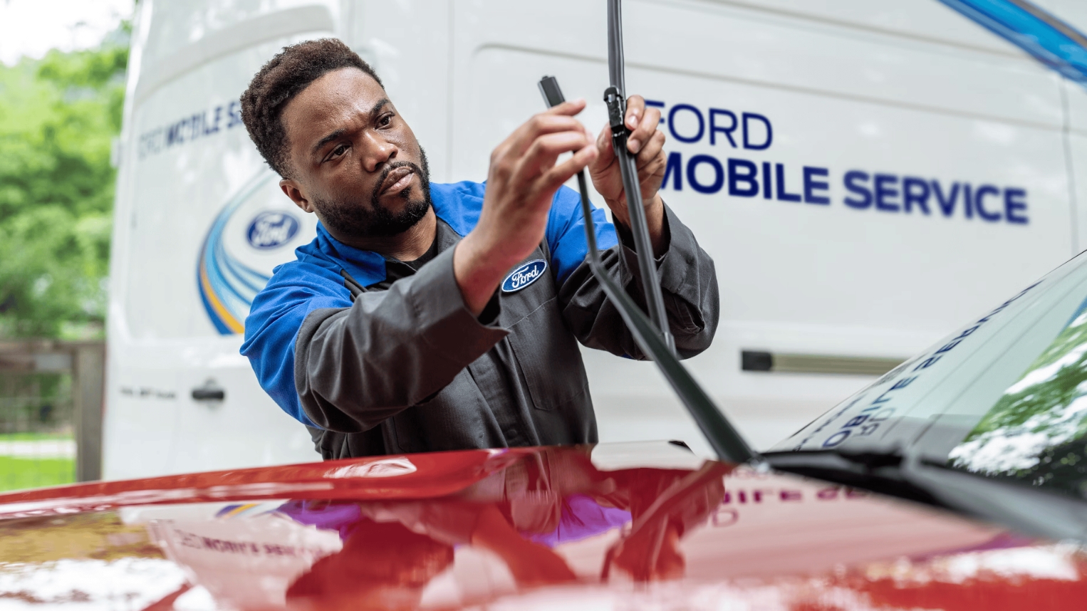Ford Mobile Service technician replacing windshield wiper blades on vehicle at home