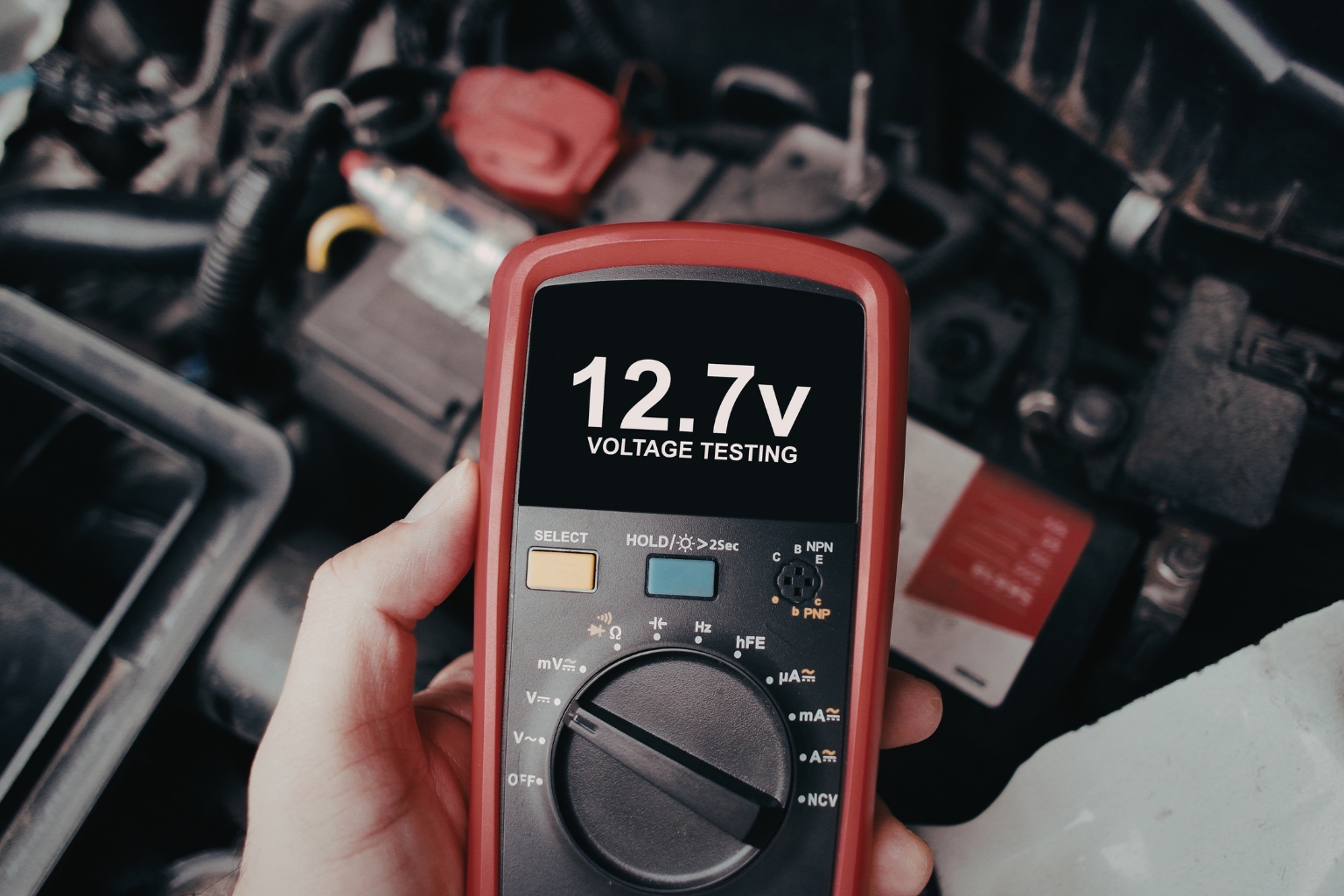Technician performing battery voltage test during mobile vehicle service inspection