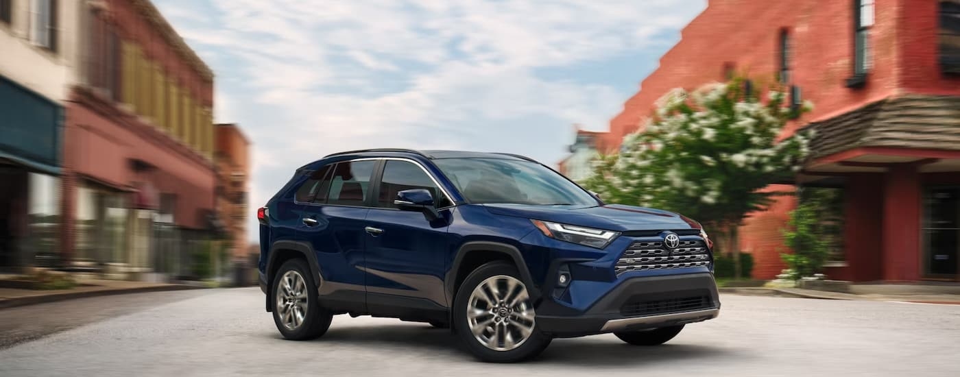 A blue 2025 Toyota RAV4 driving in a city
