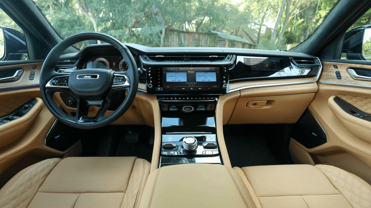 2026 Jeep Grand Cherokee interior in Margate FL featuring dual McIntosh touchscreen infotainment system, tan quilted leather seats, and panoramic dashboard view