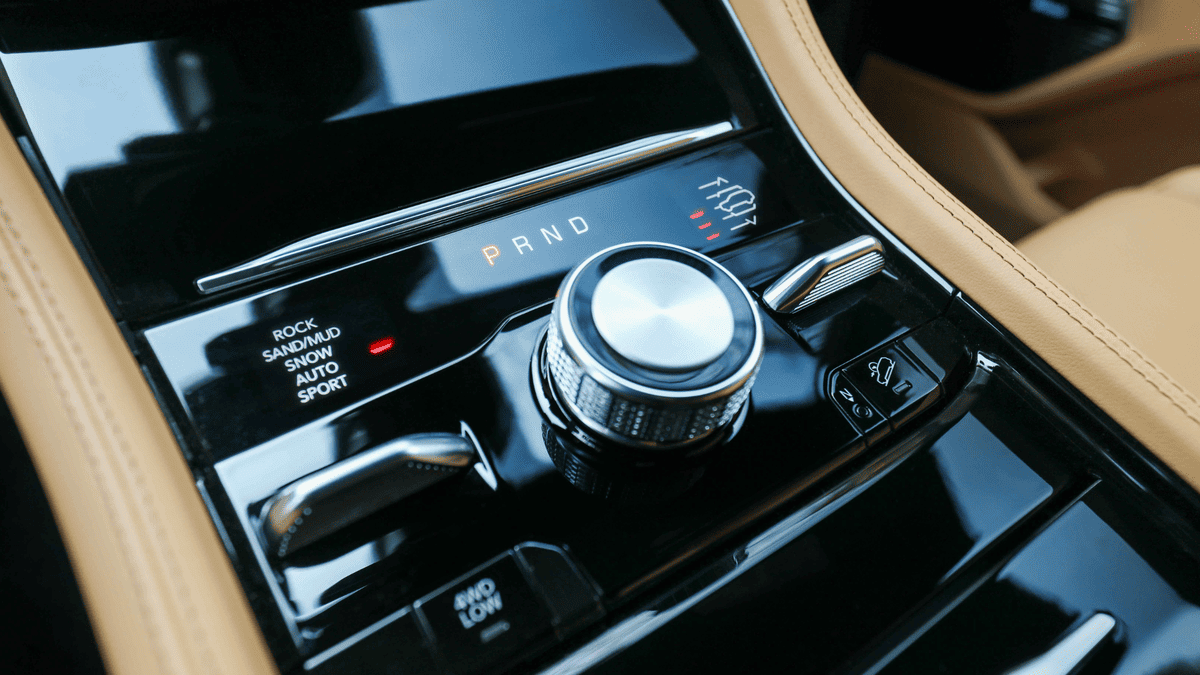 2026 Jeep Grand Cherokee center console in Margate FL showing rotary gear selector with PRND display and Rock, Sand/Mud, Snow, Auto, Sport drive modes on tan leather interior