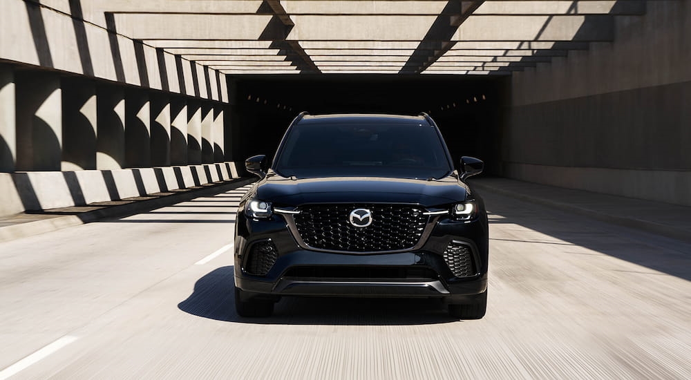 Front of a black 2026 Mazda CX-70 driving down an open road.