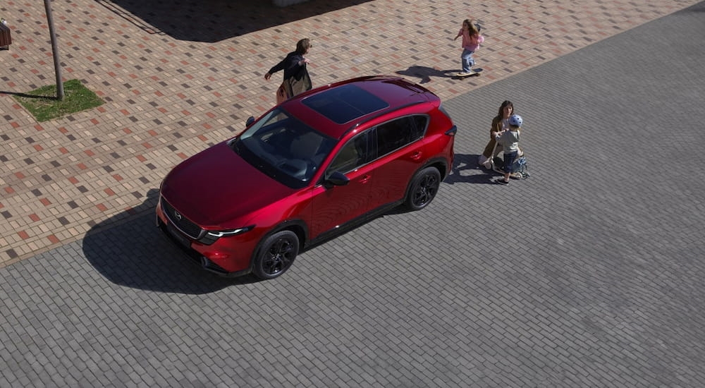 Red 2026 Mazda CX-5 driving down a city street.