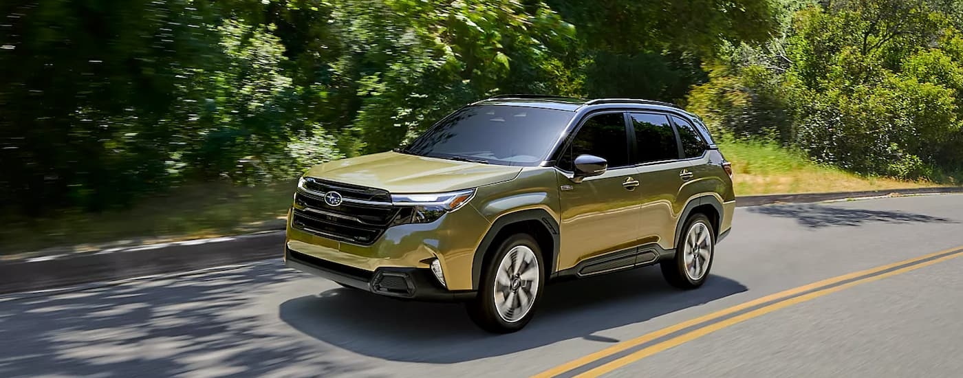 Yellow 2025 Subaru Forester driving down a road.