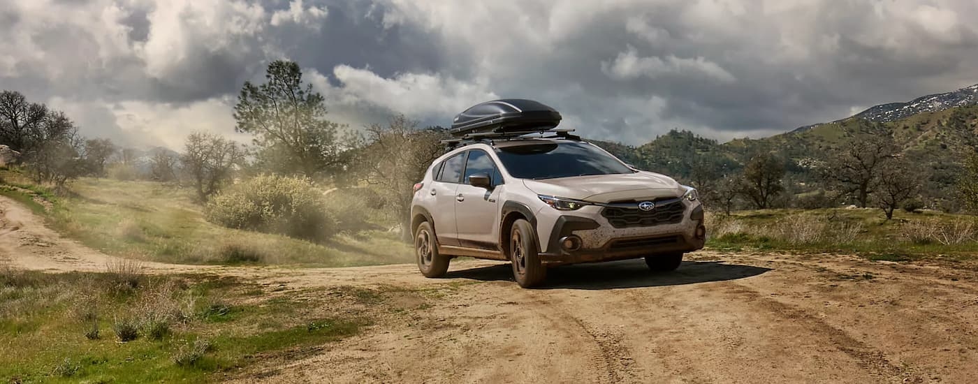 Silver 2026 Subaru Crosstrek Hybrid driving off-road down a dirt road.