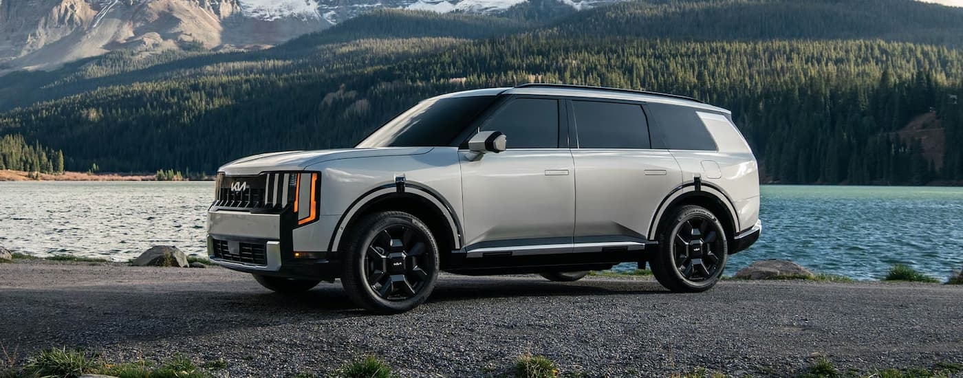 White 2026 Kia Telluride parked off-road near a lake.