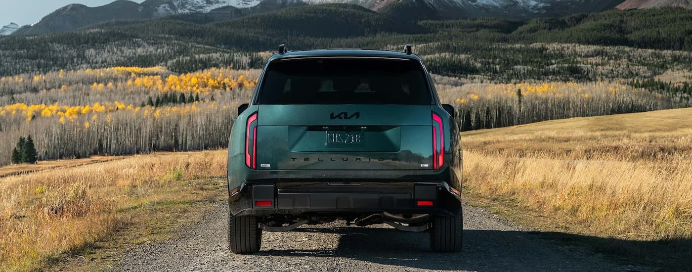 Rear of a dark green 2026 Kia Telluride driing off-road.