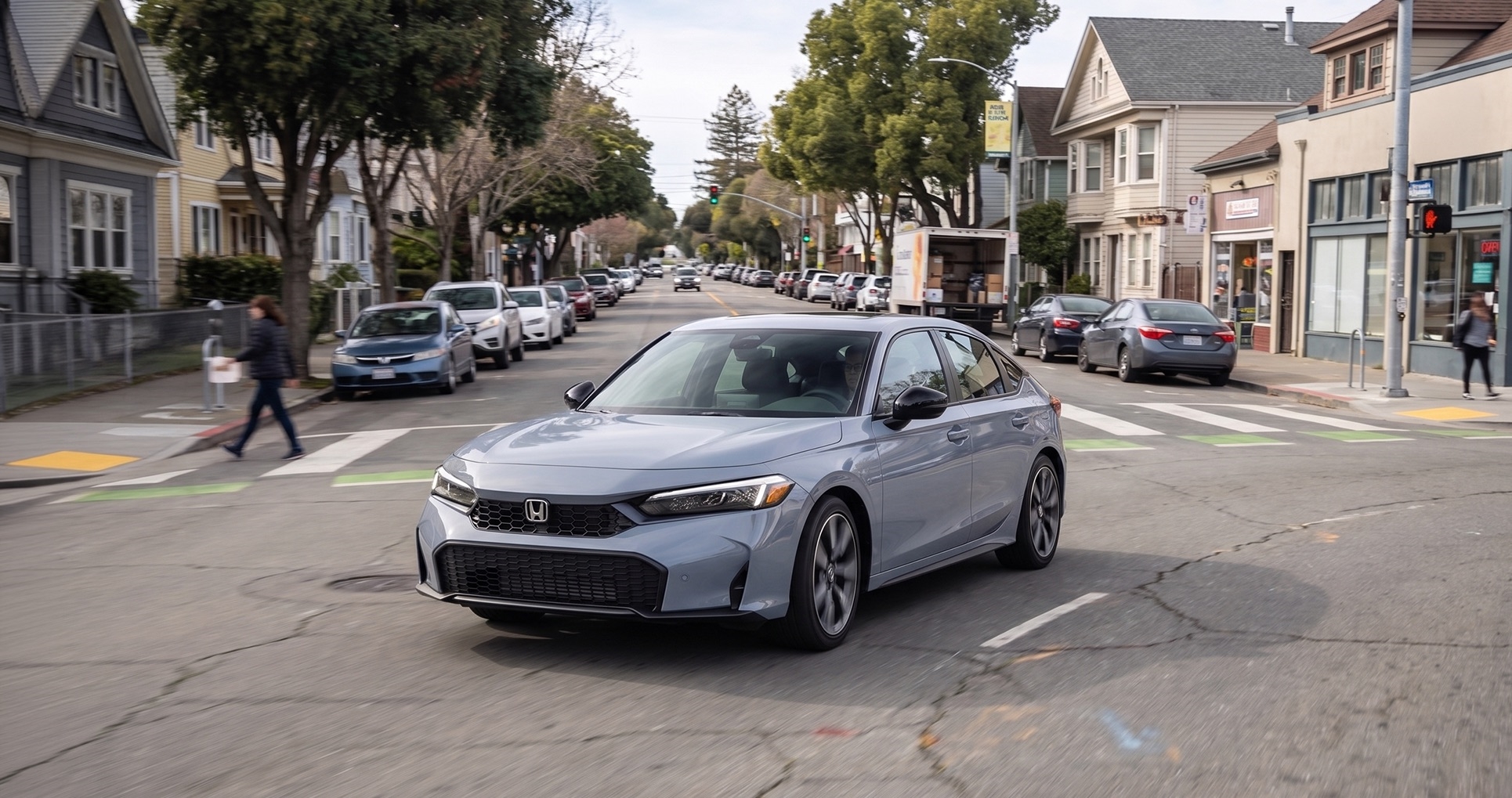 2026 Honda Civic driving through an East Bay neighborhood street with stoplights and crosswalks, showing efficient city commuting and everyday driving