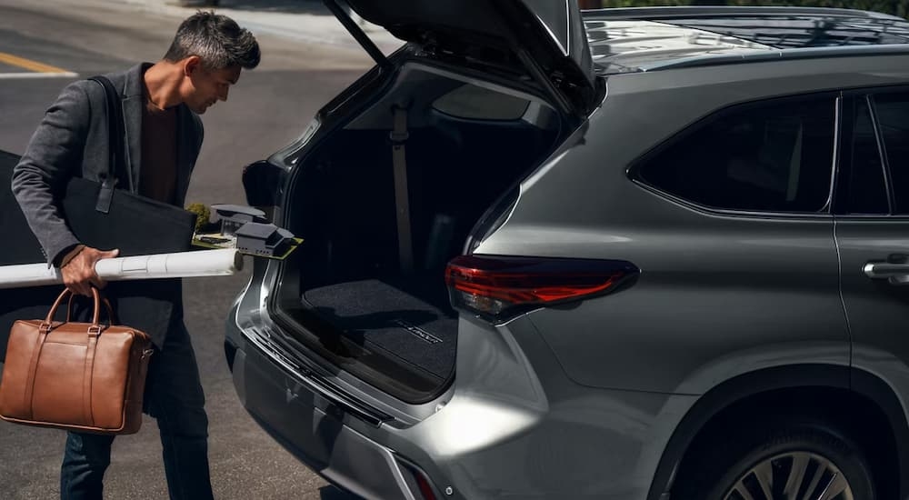 Man putting items in the trunk of a grey 2026 Toyota Highlander