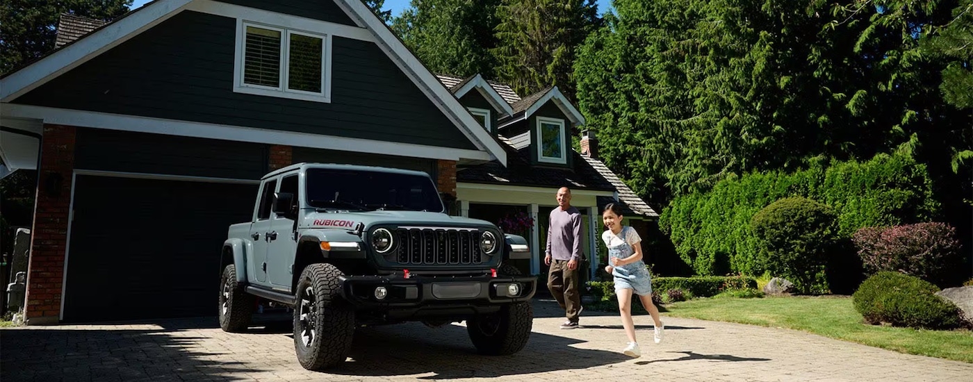 Grey 2024 Jeep Gladiator Rubicon X parked on a driveway outside a house.