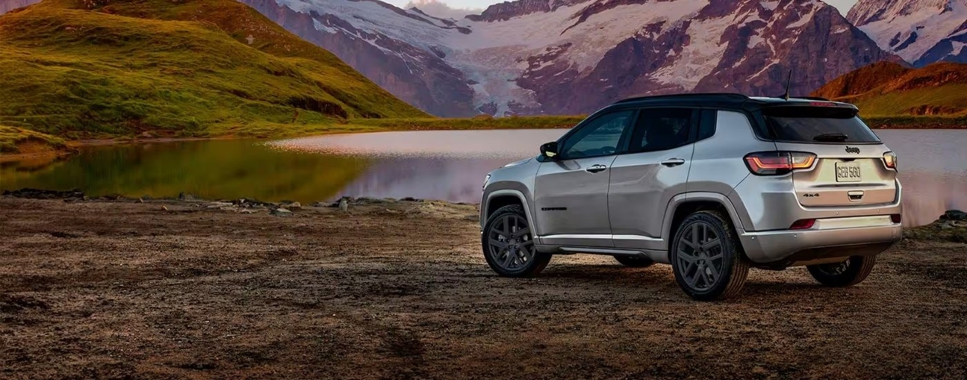 Rear of a silver 2026 Jeep Compass parked near a lake.